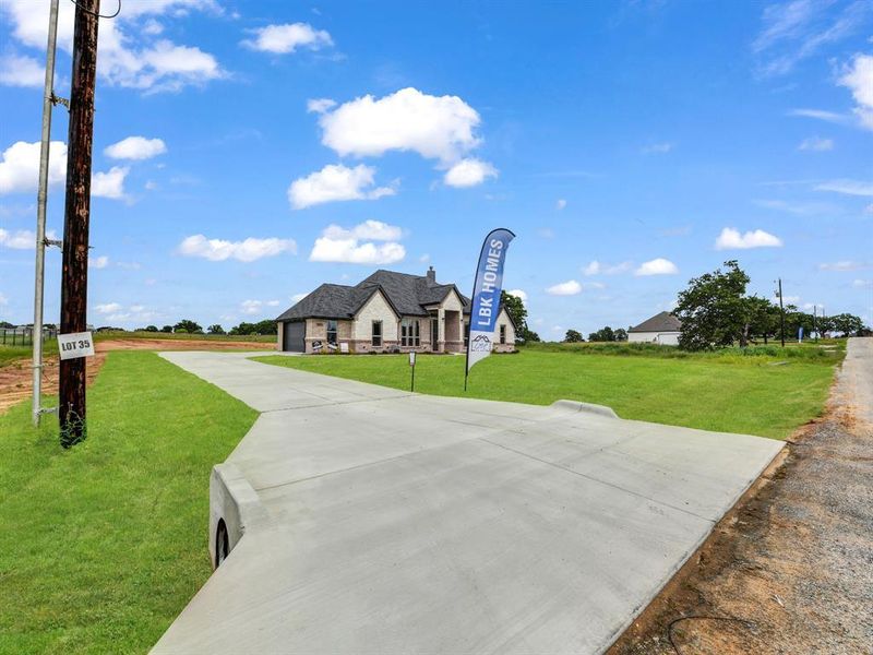 View of front of home with a front lawn, stone siding, and driveway