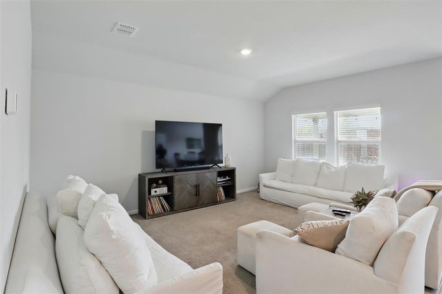 Living area with carpet, lofted ceiling, baseboards, and recessed lighting.