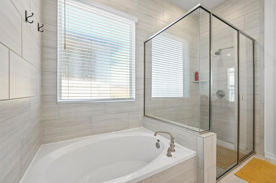 An inviting soaking tub pairs beautifully with a modern glass-enclosed walk-in shower.