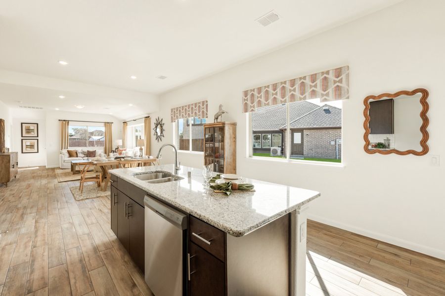 Kitchen island with granite countertop and sink, open to dining and living area with wood floors