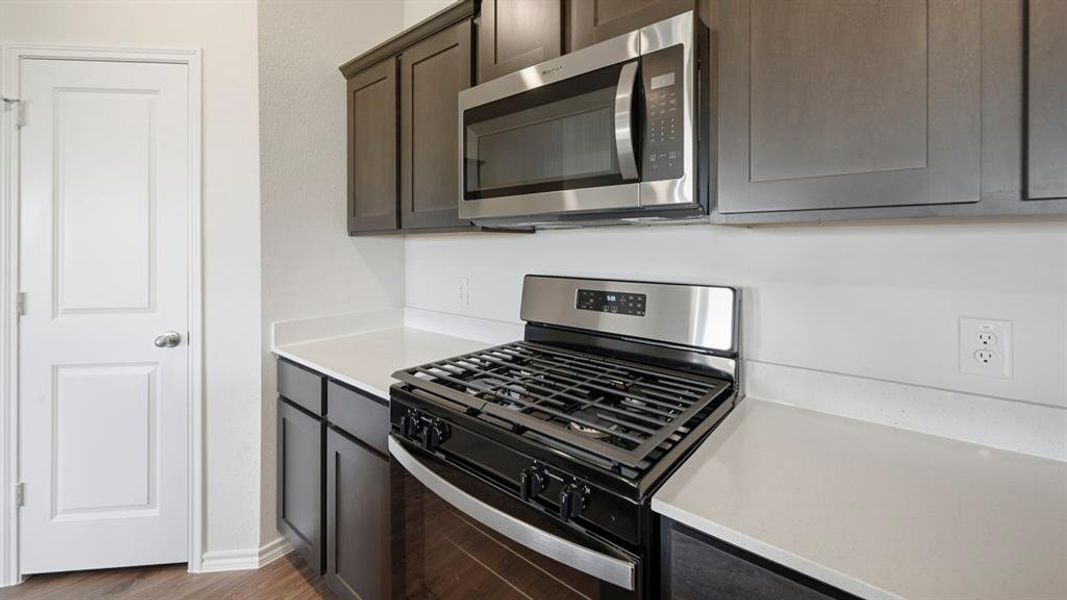 Kitchen featuring stainless steel appliances, dark wood finished floors, and light stone countertops