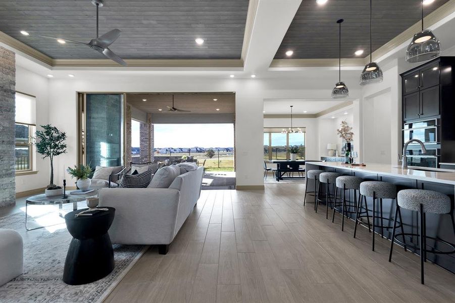 Living room with a ceiling fan, a raised ceiling, light wood finished floors, wood ceiling, and ornamental molding