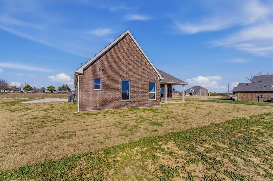 Rear view of property with a yard, brick siding, and a patio area
