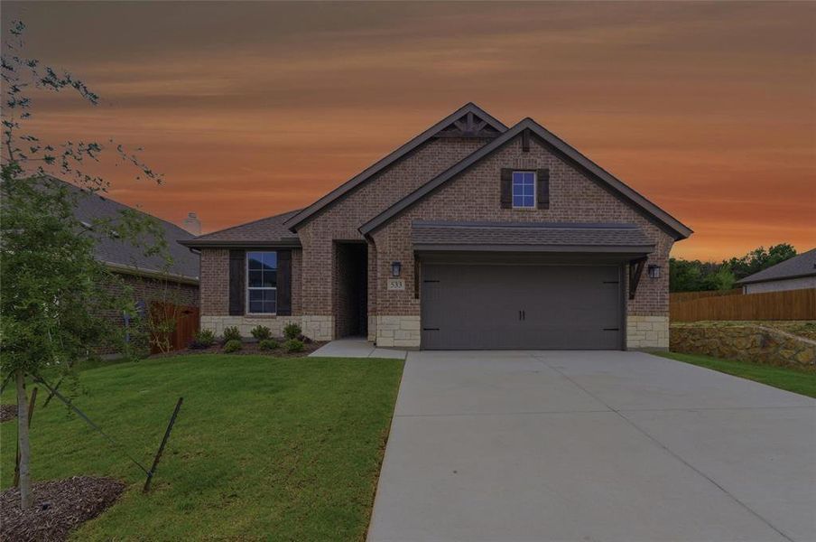 Brick and stone facade residence featuring a two-car garage, manicured front lawn, and concrete driveway