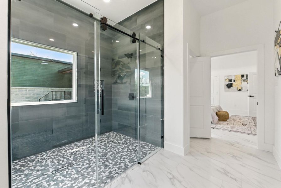 Primary bathroom with a shower stall with a mosaic tile floor.