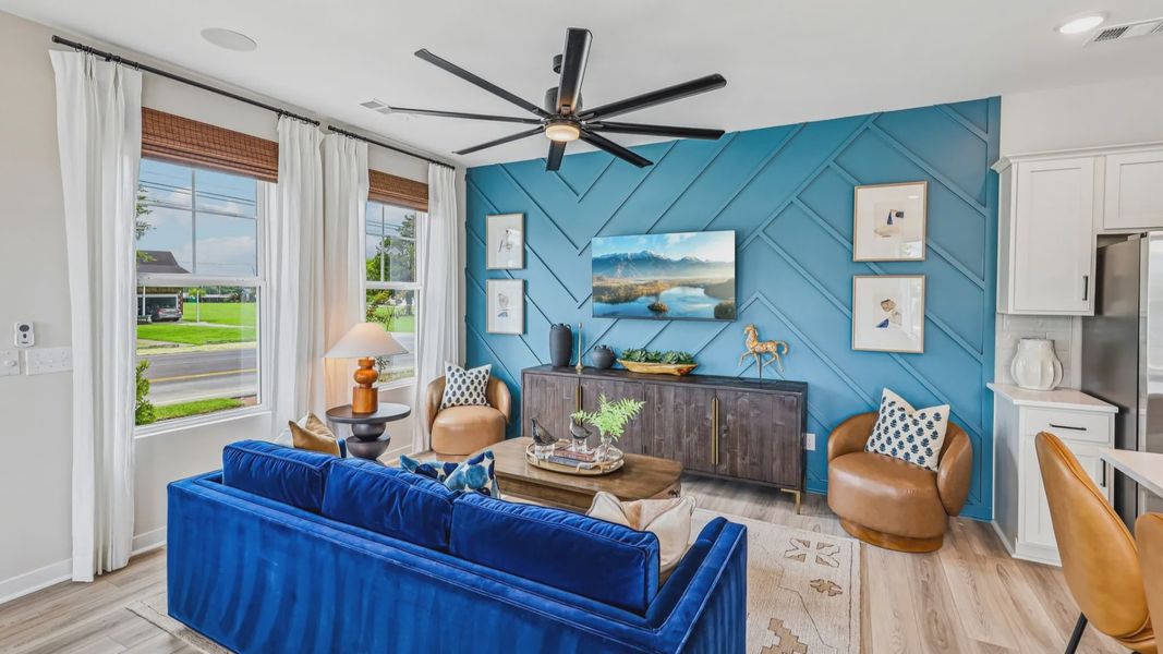 Gathering room with ceiling fan, hard surface flooring, and accent wall
