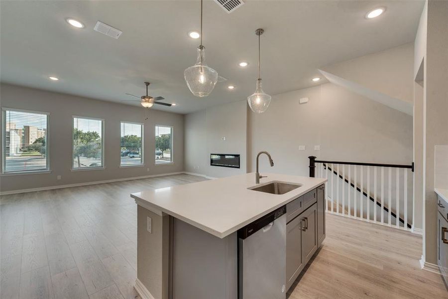 Kitchen with pendant lighting, an island with sink, light wood-type flooring, sink, and dishwasher