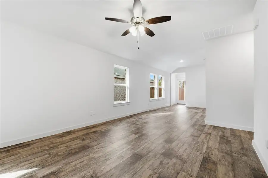 Unfurnished living room with dark wood-style flooring, vaulted ceiling, ceiling fan, and recessed lighting Unfurnished living room with dark wood-style flooring, vaulted ceiling, ceiling fan, and recessed lighting