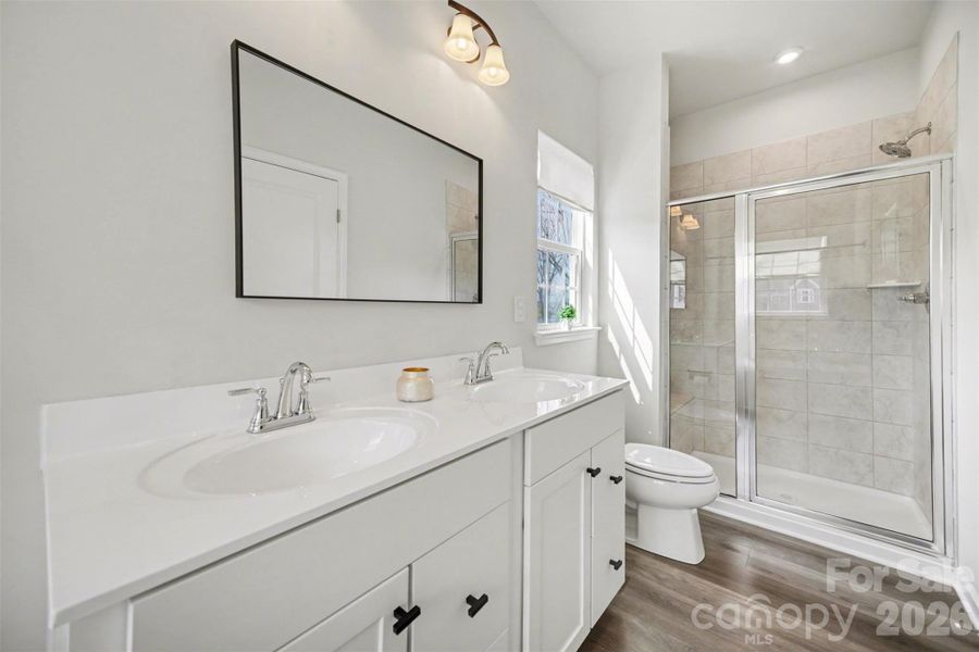 Bright primary bathroom with dual vanity and spacious walk-in shower
