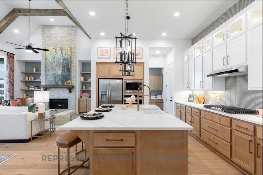 Kitchen with open floor plan, a kitchen bar, light brown cabinetry, an island with sink, and high vaulted ceiling