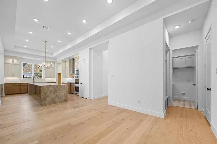 Kitchen featuring glass insert cabinets, recessed lighting, a center island, a raised ceiling, and light wood-type flooring Kitchen featuring glass insert cabinets, recessed lighting, a center island, a raised ceiling, and light wood-type flooring