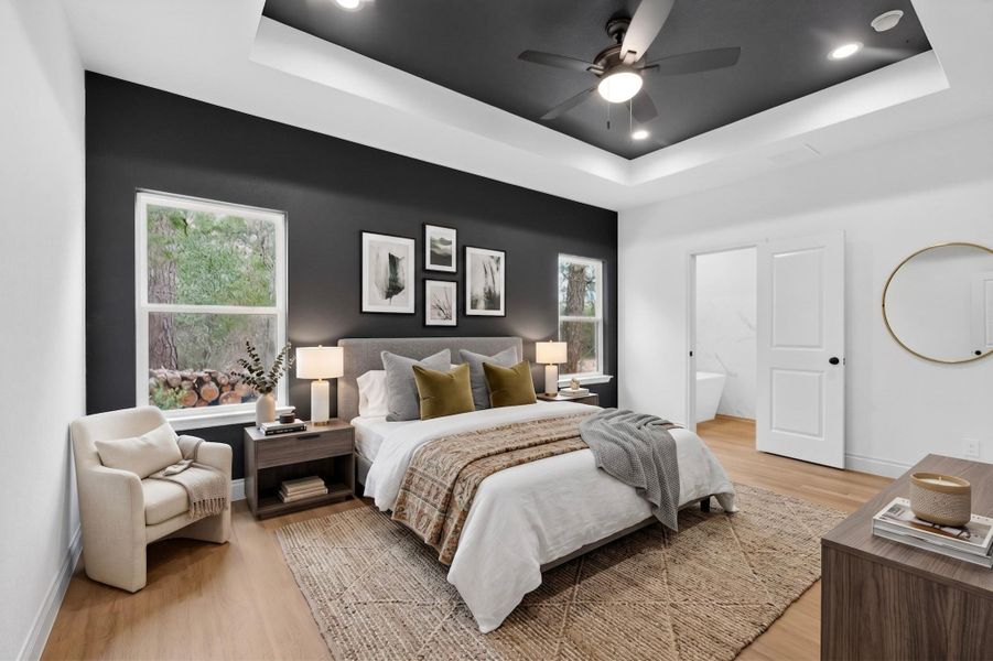 Bedroom featuring a tray ceiling with recessed lighting and a ceiling fan, wood-finish flooring, and a window with a wooded backdrop Bedroom featuring a tray ceiling with recessed lighting and a ceiling fan, wood-finish flooring, and a window with a wooded backdrop
