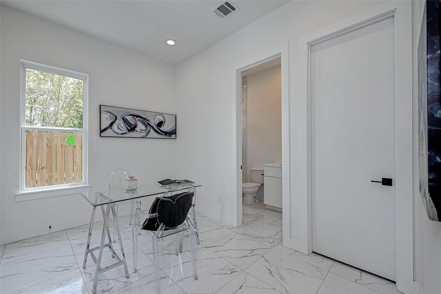 This versatile space on the first level is perfect as a guest bedroom or stylish home office. With marble-look tile flooring, natural light, and a private en-suite bath, it offers both function and flair for work or rest.