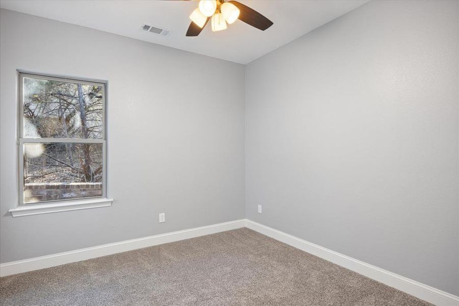 Secondary front room with carpet floors and ceiling fan