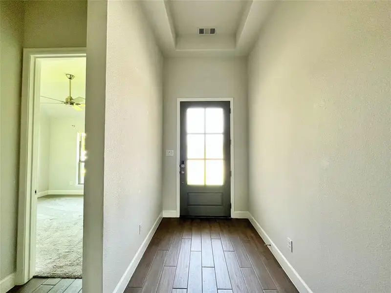 Entryway featuring wood finished floors, a textured wall, and a ceiling fan Entryway featuring wood finished floors, a textured wall, and a ceiling fan