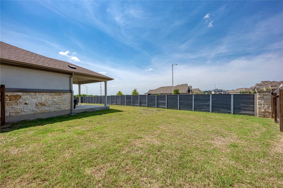 A spacious backyard with a covered patio offers ample room for outdoor activities.