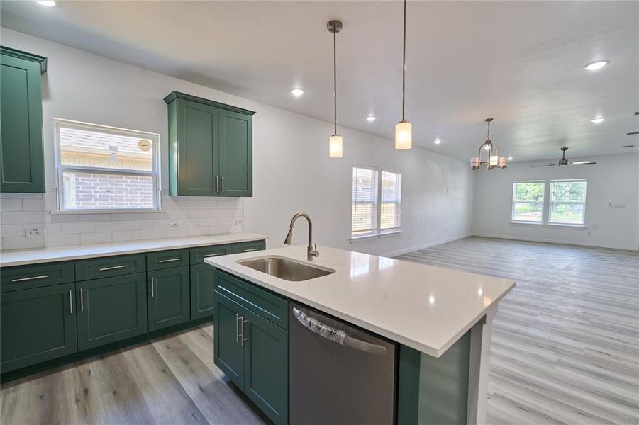 Kitchen featuring deep green cabinetry, white countertops, subway tile backsplash, and a stainless steel sink with a gooseneck faucet