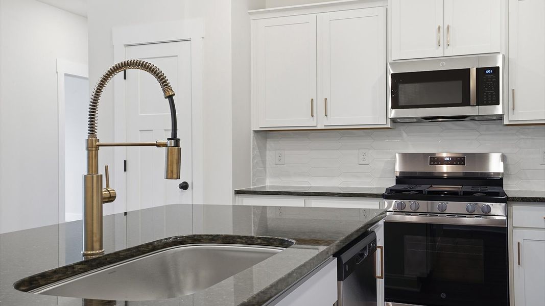 Tasteful kitchen with oversized island and granite countertops—crafted to high standards at Village at Midway Tasteful kitchen with oversized island and granite countertops—crafted to high standards at Village at Midway