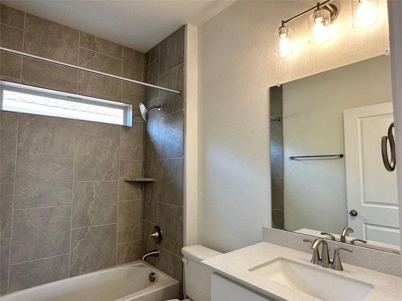 Bathroom with shower / washtub combination, vanity, and a textured wall