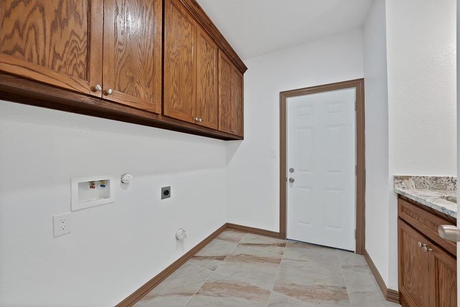 Laundry room with hookup for a gas dryer, electric dryer hookup, washer hookup, light marble finish floors, and cabinet space