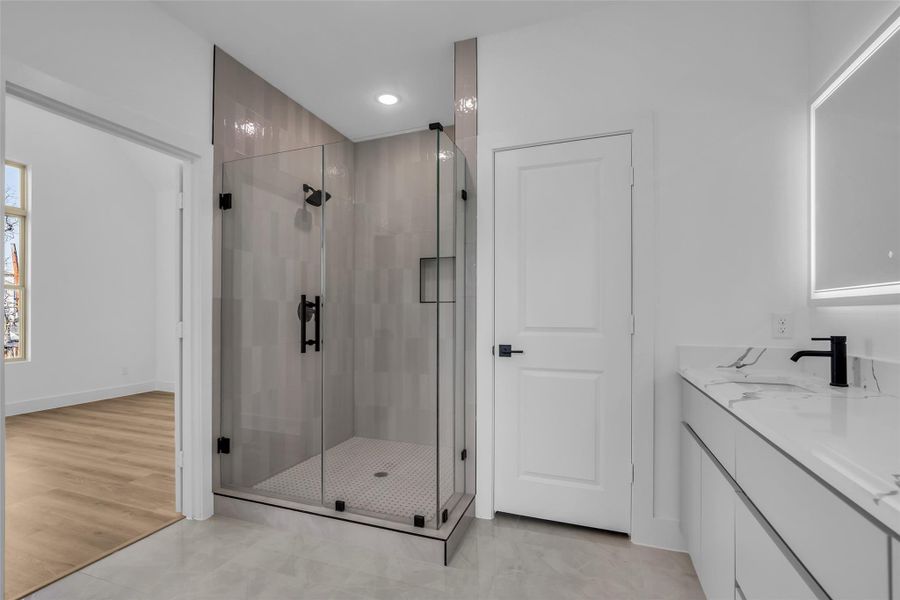 Thoughtfully crafted spa like primary bath, large walk-in shower with beautiful tile walls and flooring, frameless glass surround, marble flooring, dual quartz vanity, and custom soft close cabinetry. Thoughtfully crafted spa like primary bath, large walk-in shower with beautiful tile walls and flooring, frameless glass surround, marble flooring, dual quartz vanity, and custom soft close cabinetry.