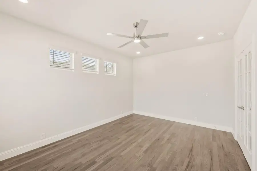Empty room with hardwood floors, ceiling fan, recessed lighting, and three small windows
