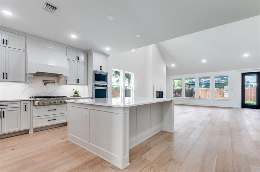 Kitchen featuring light wood-type flooring, white cabinetry, decorative backsplash, recessed lighting, and plenty of natural light