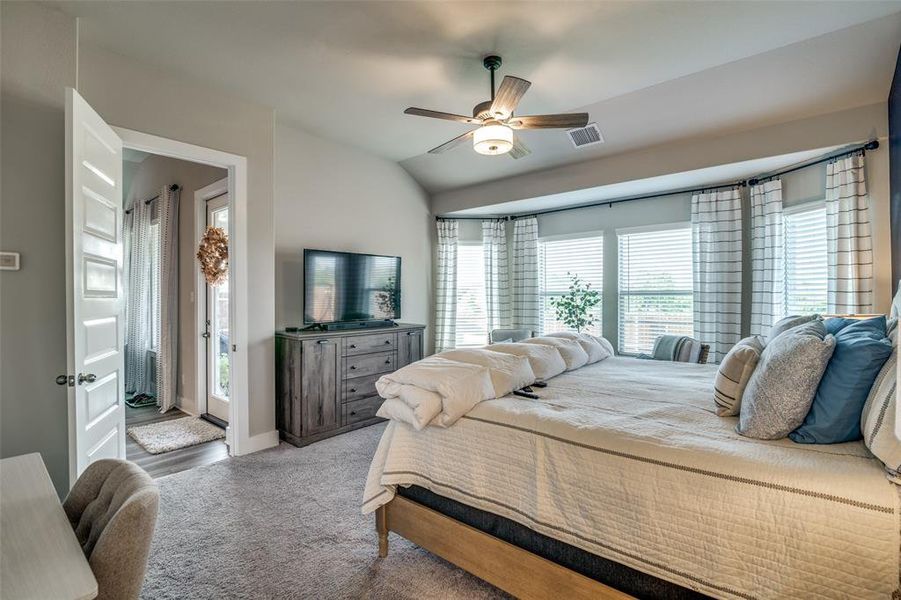 Carpeted bedroom featuring access to outside, vaulted ceiling, and ceiling fan