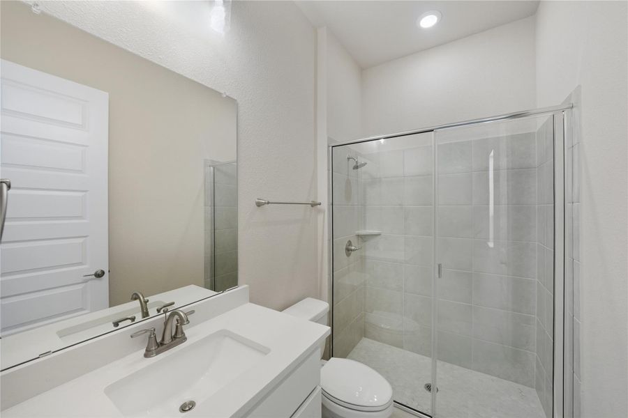 Bathroom with a shower stall, vanity, and recessed lighting