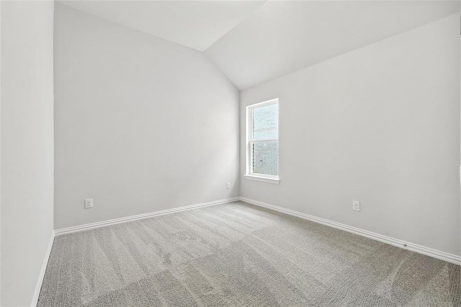 Spare room featuring light colored carpet and vaulted ceiling