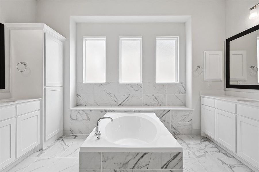 Full bath featuring two vanities and a garden tub