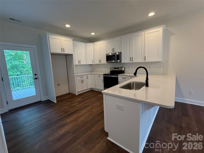 The kitchen offers a spacious breakfast bar, access to the back deck through a glass door,...