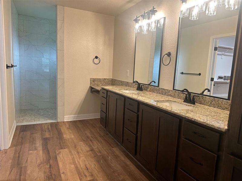 Full bathroom with wood finished floors, double vanity, walk in shower, and a spacious closet Full bathroom with wood finished floors, double vanity, walk in shower, and a spacious closet