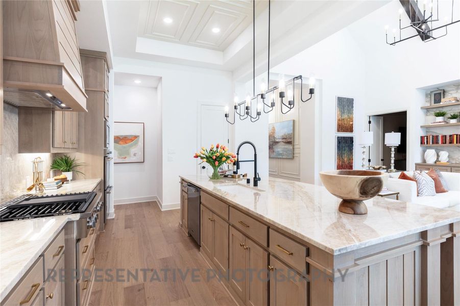 Kitchen with a sink, a chandelier, custom exhaust hood, and a raised ceiling Kitchen with a sink, a chandelier, custom exhaust hood, and a raised ceiling