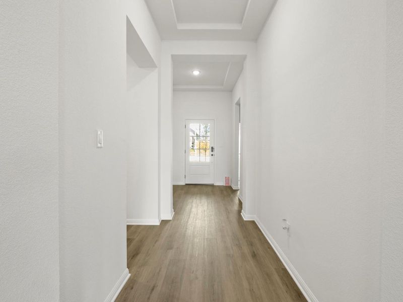 Entryway featuring wood-finish flooring, white baseboards, a coffered ceiling, and a paneled door with decorative glass inserts