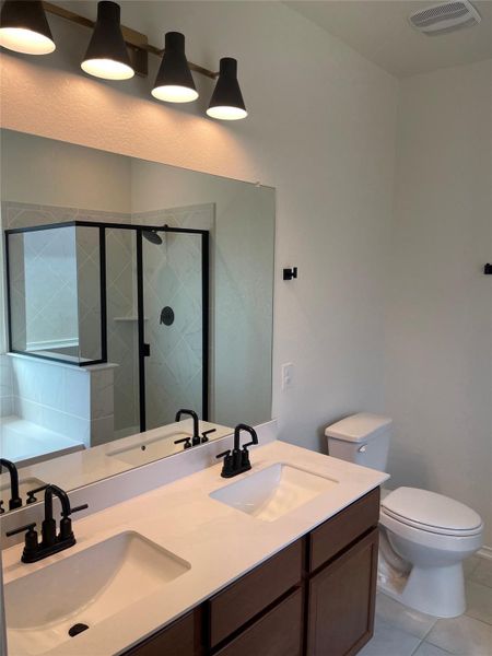 Bathroom featuring a shower stall, light tile patterned flooring, and double vanity Bathroom featuring a shower stall, light tile patterned flooring, and double vanity