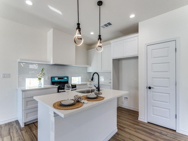 Kitchen featuring stove, sink, an island with sink, and dark hardwood / wood-style flooring