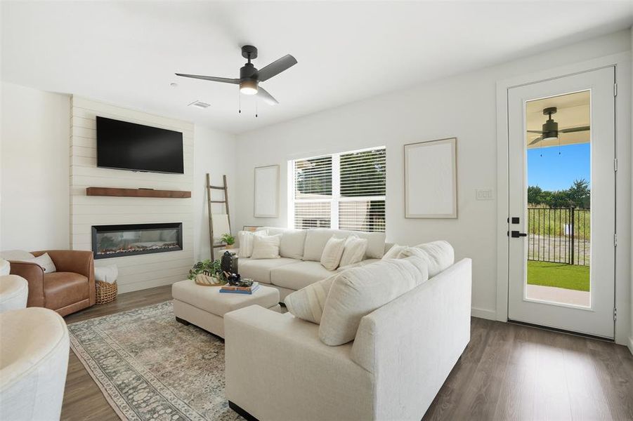 Living room featuring ceiling fan, wood finished floors, and a large fireplace Living room featuring ceiling fan, wood finished floors, and a large fireplace
