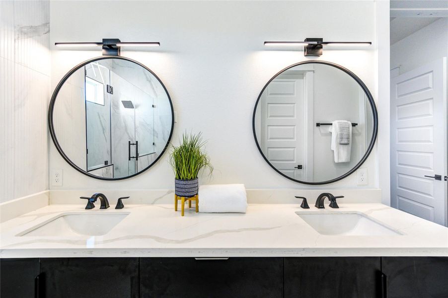 Primary bathroom featuring double vanity sinks with quartz countertops, adjustable anti-fog mirrors, and tile flooring. Highlights include 10-ft ceilings, a freestanding soaking tub, chandelier accent lighting, and a frameless shower with floor-to-ceiling tile.