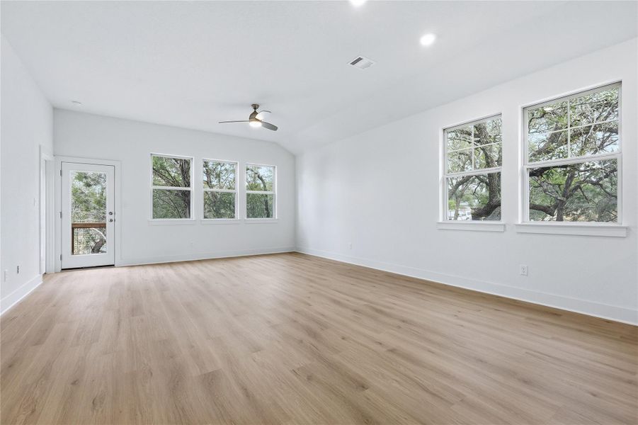 Unfurnished living room featuring light wood finished floors, ceiling fan, lofted ceiling, and recessed lighting