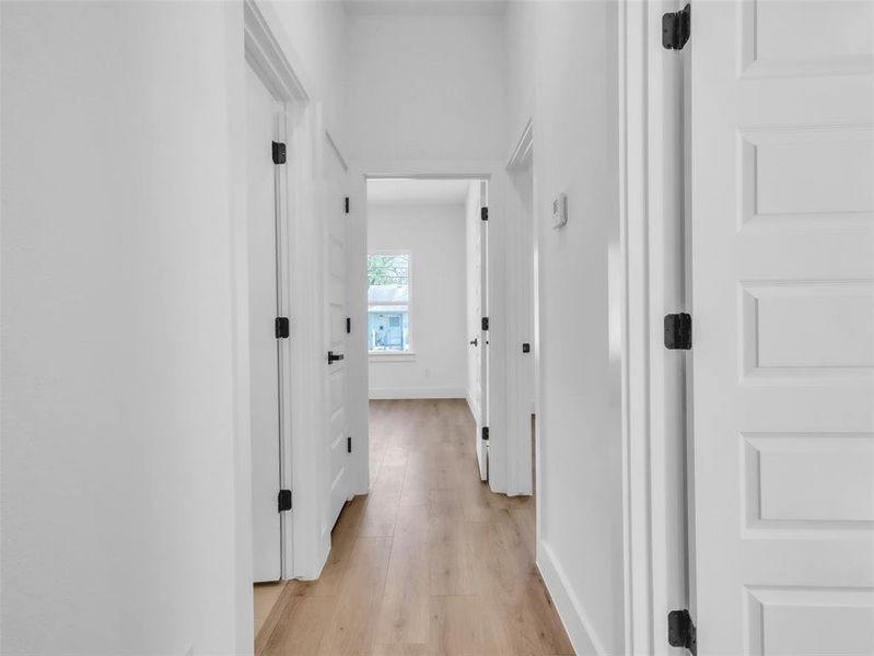 Hallway with light wood-style flooring and baseboards Hallway with light wood-style flooring and baseboards