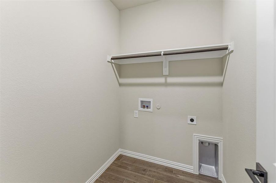 Dedicated utility space with wood-finish flooring, white baseboards, and light-toned walls