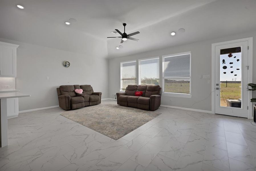 Living area featuring marble look floor tile, recessed lighting, and baseboards