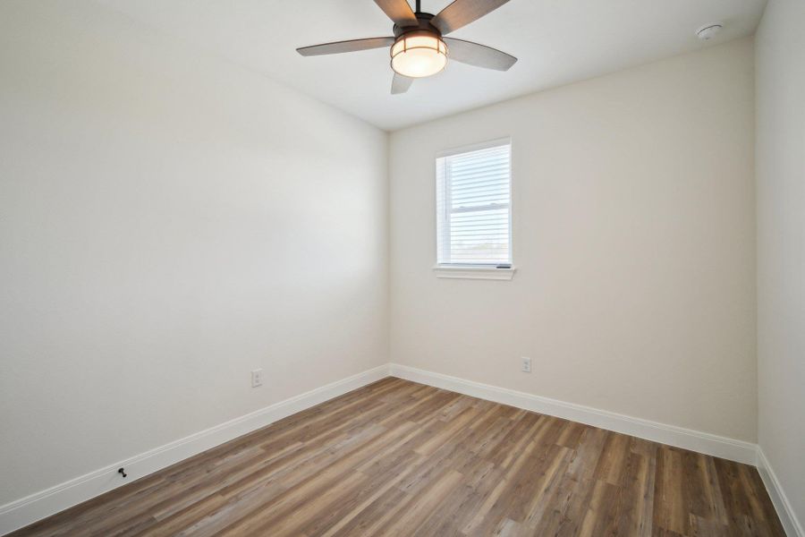 Bedroom 4 with baseboards, wood finished floors, and a ceiling fan Bedroom 4 with baseboards, wood finished floors, and a ceiling fan