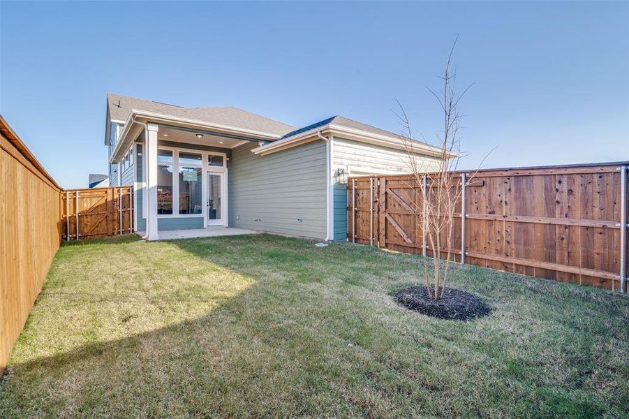 Rear view of house featuring a lawn, a patio area, and french doors