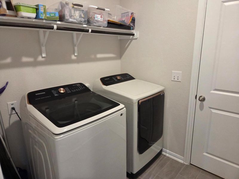 Dedicated laundry area featuring a white door, light-toned walls, and gray tile flooring