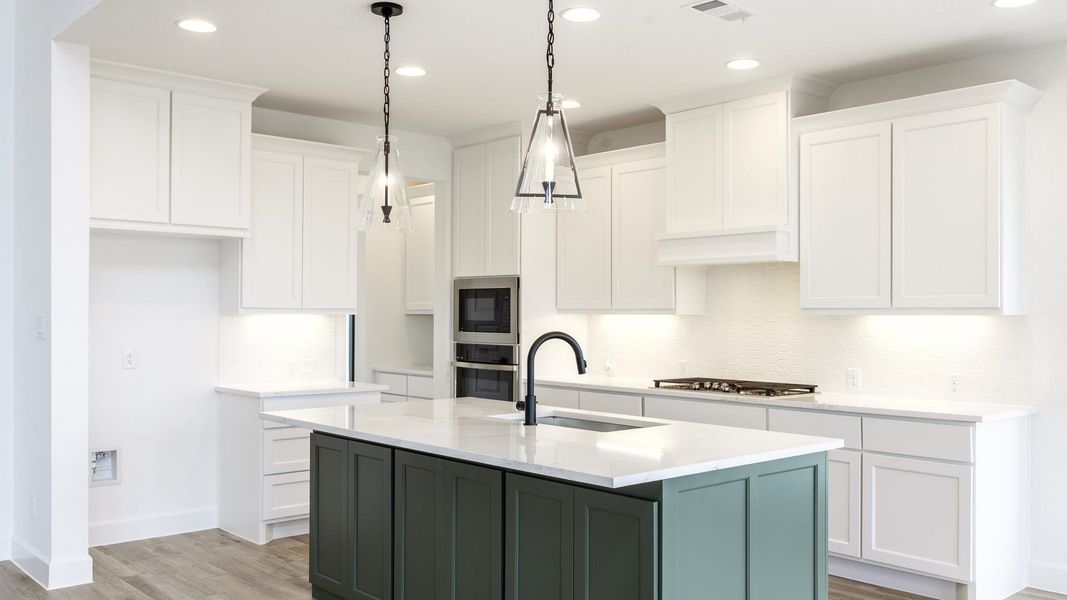 Kitchen with white cabinetry, green cabinets, light wood-style floors, recessed lighting, and a center island with sink