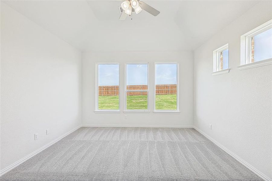 Carpeted empty room with ceiling fan and a healthy amount of sunlight