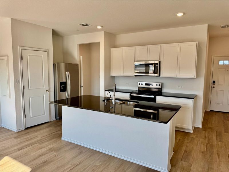 Kitchen with white cabinets, an island with sink, stainless steel appliances, light wood-type flooring, and recessed lighting Kitchen with white cabinets, an island with sink, stainless steel appliances, light wood-type flooring, and recessed lighting