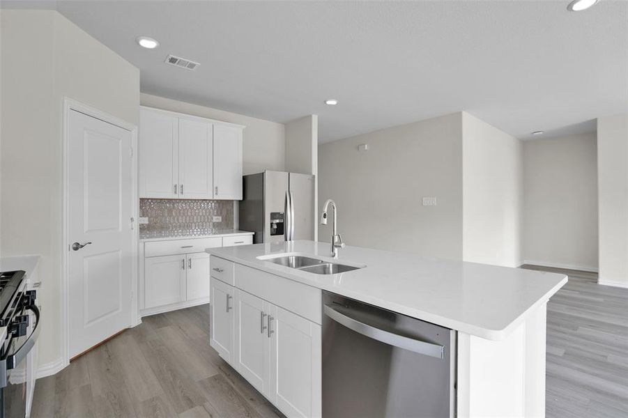 Kitchen with appliances with stainless steel finishes, decorative backsplash, white cabinetry, light wood-type flooring, and recessed lighting Kitchen with appliances with stainless steel finishes, decorative backsplash, white cabinetry, light wood-type flooring, and recessed lighting